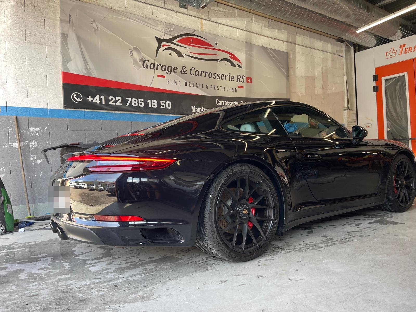 Porsche 911 noire à la finition brillante dans l'atelier Carrosserie RS Suisse